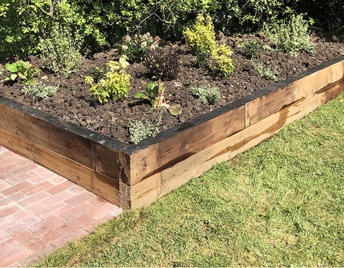 Wooden sleeper flower bed with a new paved pathway.